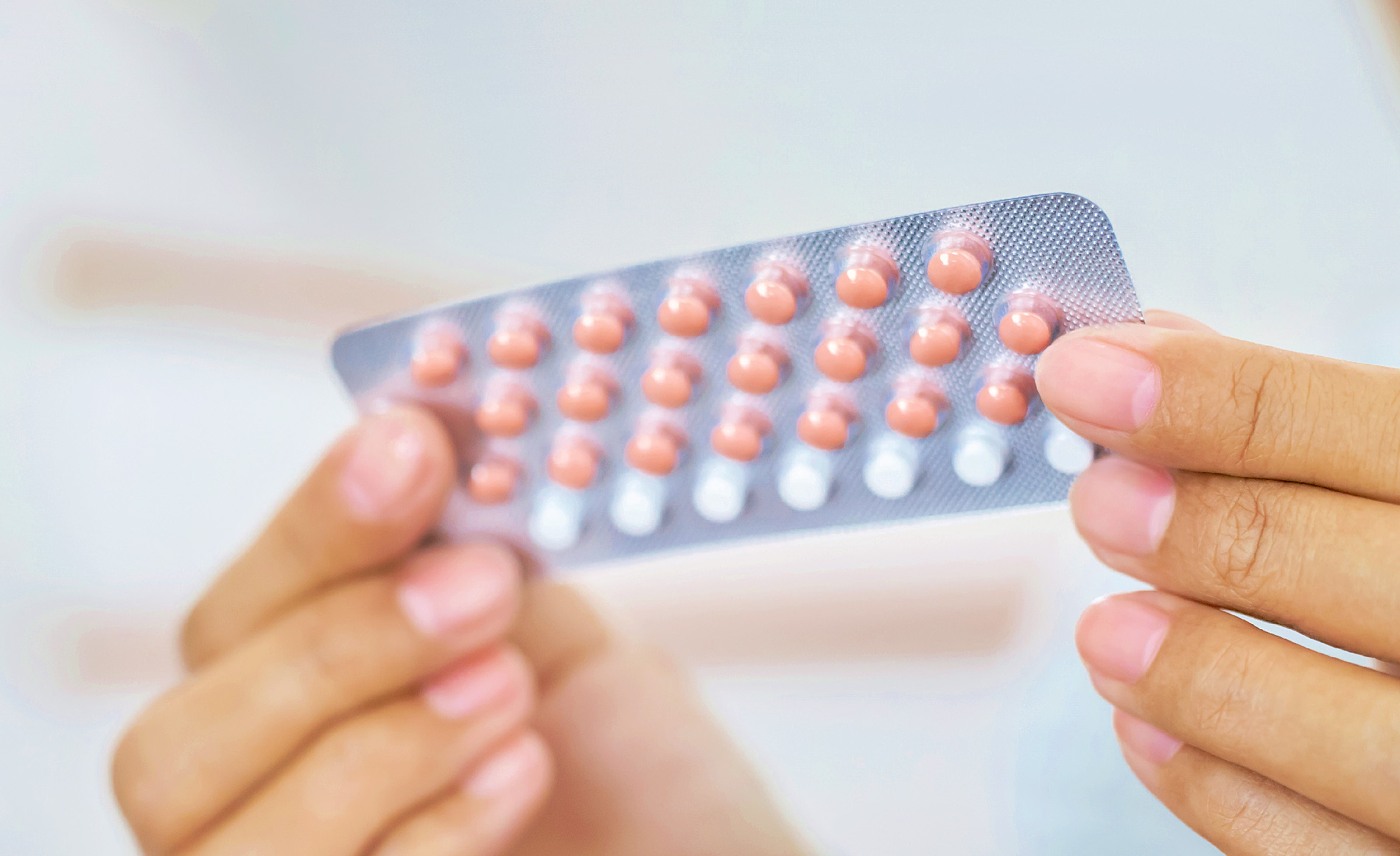 Frauenhände, die einen Blister mit Anti-Baby-Pillen halten.