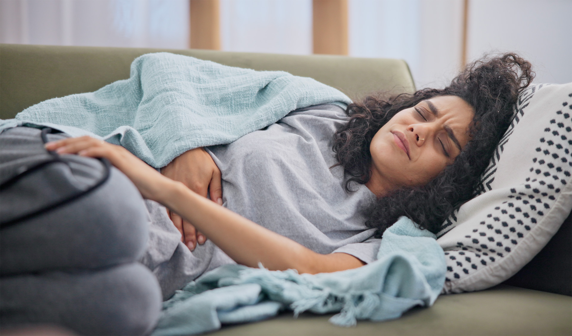 Frau mit Bauchschmerzen auf dem Sofa